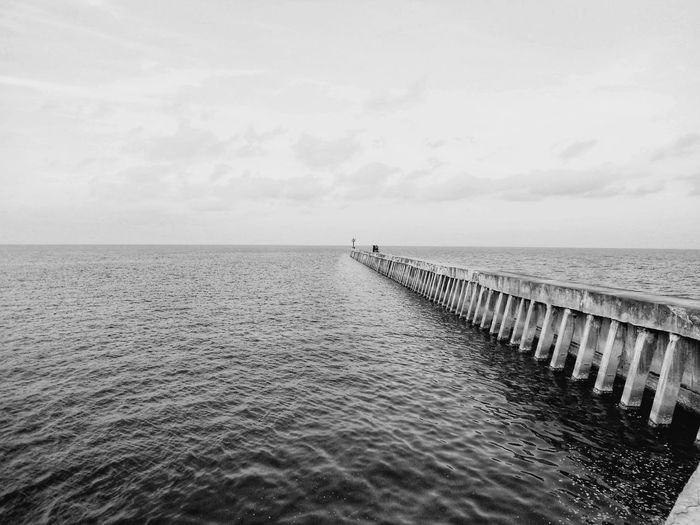 Wooden posts in sea against sky