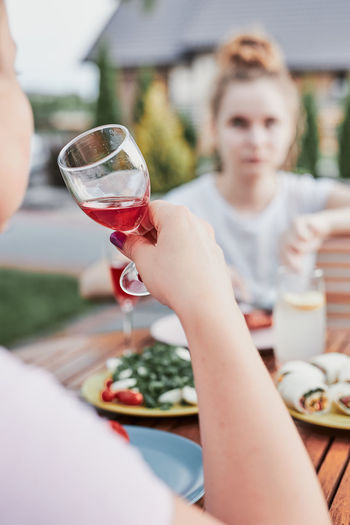 Woman drinking red wine during summer outdoor dinner in a home garden