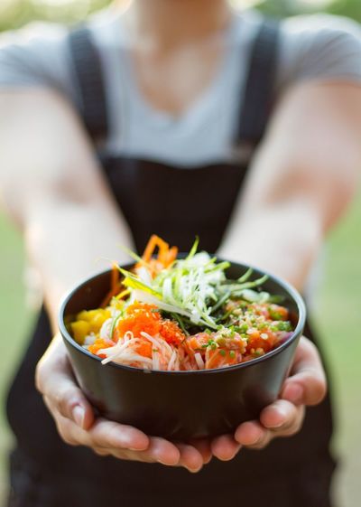 Midsection of woman holding poke bowl