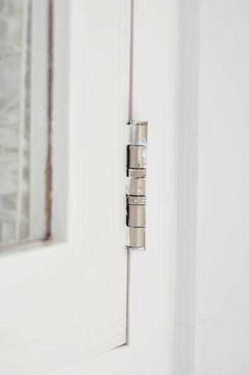 Close-up of metalic window hinge on white 