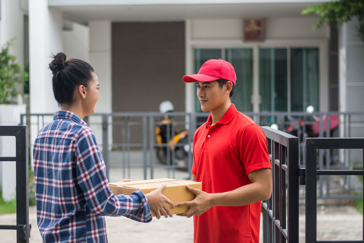 Man delivering package to female customer at gate