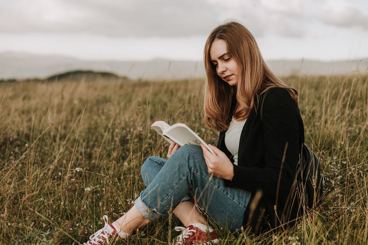 Woman reading a book outdoors on top of the mountain