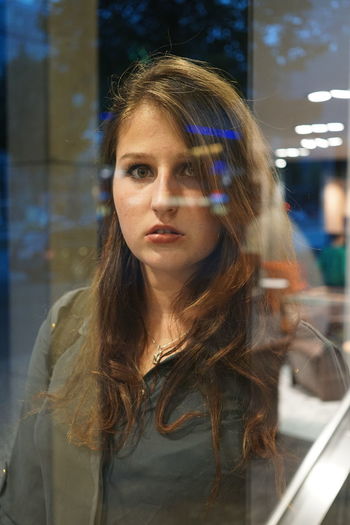 Portrait of young woman seen through glass