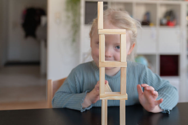 Toddler girl looking chicks through a built tower