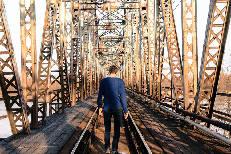 Rear view of man walking on railway bridge
