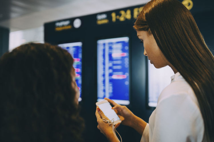 Young businesswoman checking flight timings through smart phone at airport