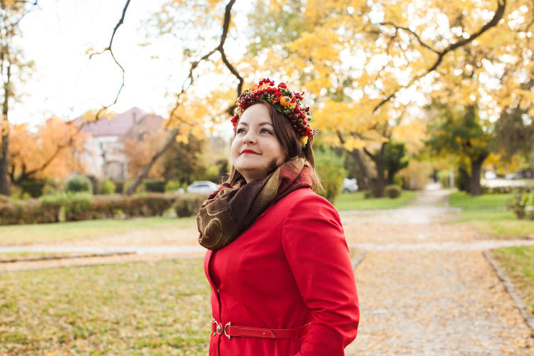 Portrait of woman standing by tree during autumn