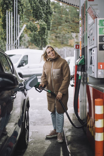 Mature woman refueling car at gas station