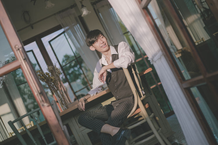 Young man looking away while sitting on chair at home