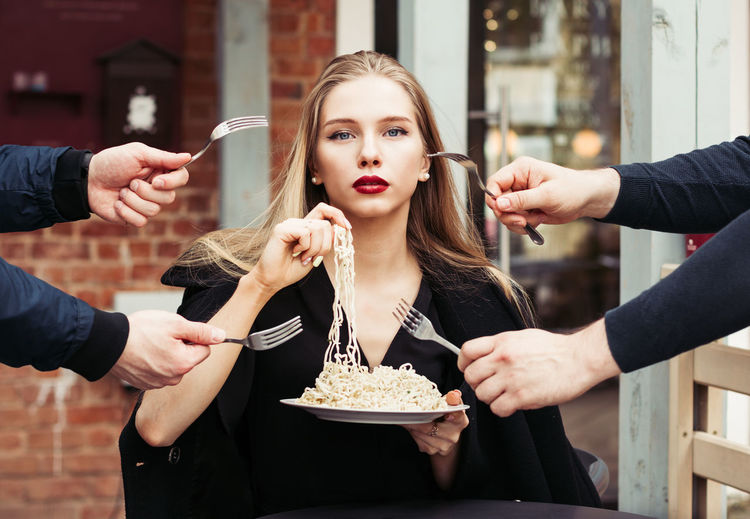 Beautiful woman eating noodles with her hands