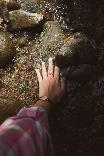 High angle view of hand on rock in the river